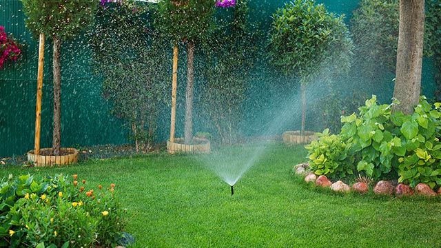 Système d'arrosage automatique en action sur une pelouse verte